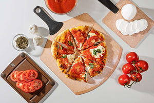 Epicurean Pizza Peel Plus in Natural with a delicious pizza and assorted toppings placed on additional Epicurean boards